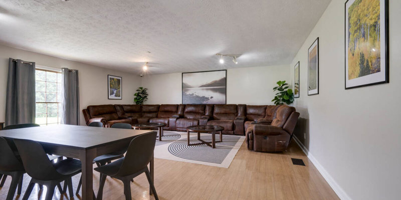 Lounge area with a large brown sectional sofa, dining table, and decor.
